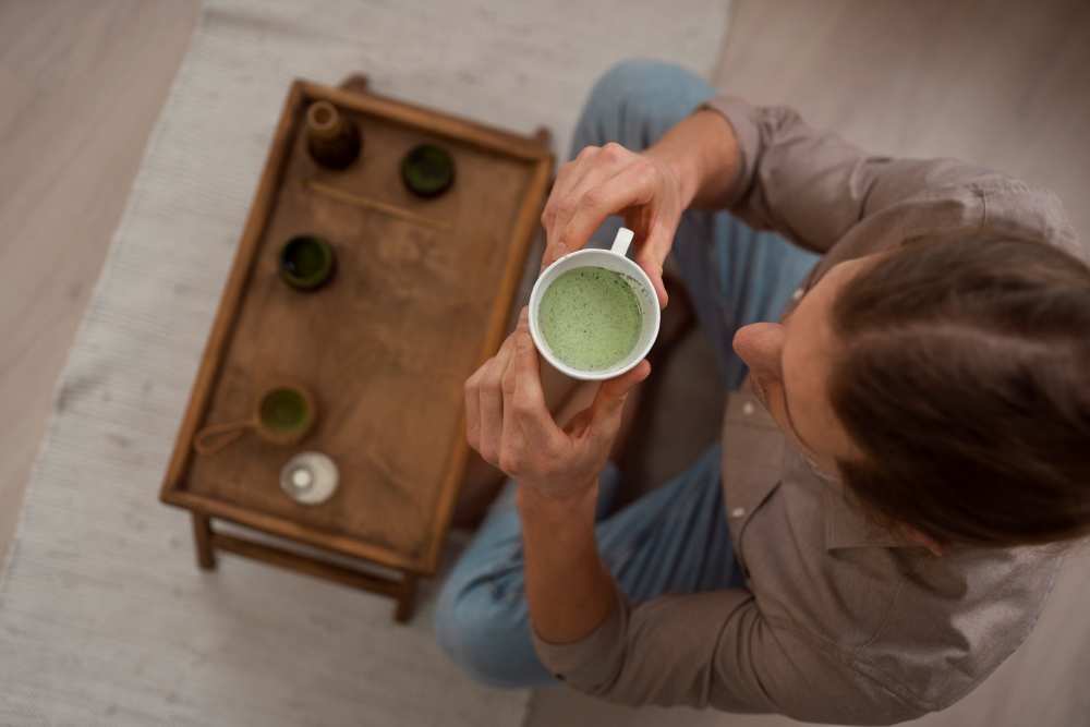 Muž, který pije zelený kratom Super Green v hrníčku 